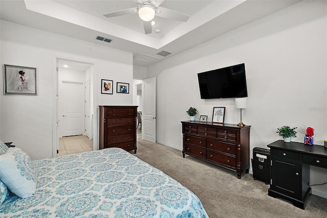 bedroom featuring a tray ceiling, light colored carpet, and ceiling fan