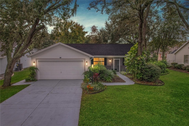 ranch-style home with a garage, a yard, and central AC