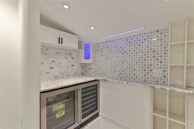 bar with lofted ceiling, white cabinets, wine cooler, decorative backsplash, and light stone countertops