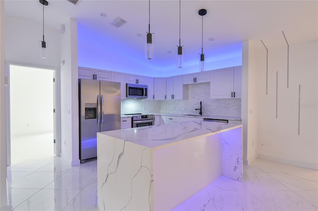 kitchen featuring pendant lighting, a center island, stainless steel appliances, and light stone counters