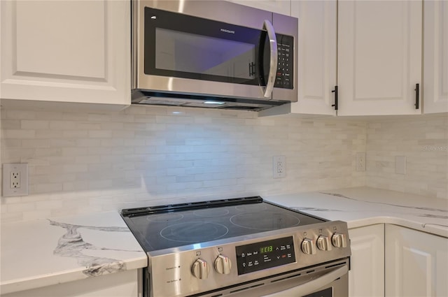 kitchen featuring white cabinets, appliances with stainless steel finishes, decorative backsplash, and light stone countertops