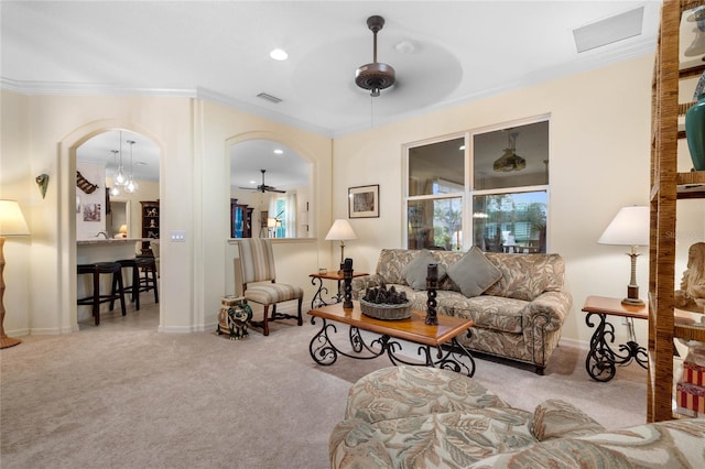 carpeted living room featuring ceiling fan with notable chandelier and ornamental molding