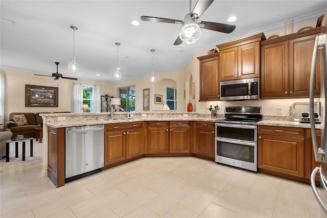 kitchen with sink, light stone counters, appliances with stainless steel finishes, crown molding, and pendant lighting