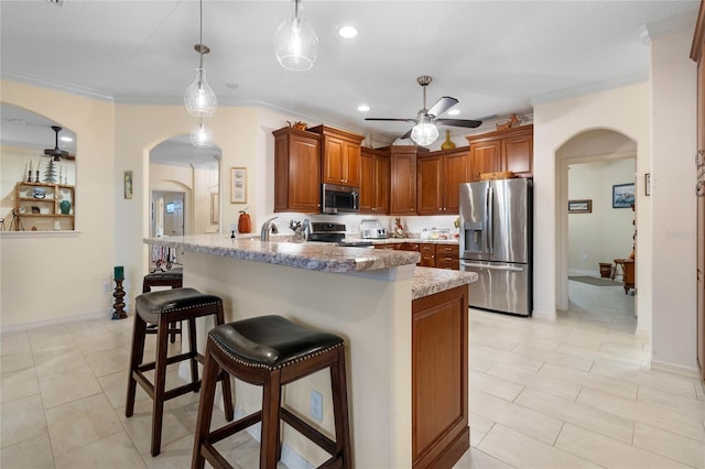 kitchen with a kitchen breakfast bar, crown molding, light stone countertops, appliances with stainless steel finishes, and decorative light fixtures