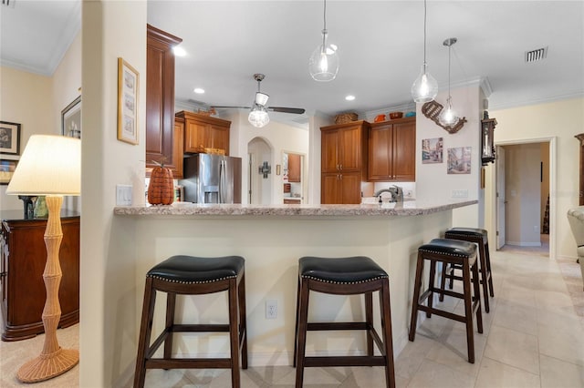 kitchen featuring a breakfast bar, kitchen peninsula, stainless steel refrigerator with ice dispenser, hanging light fixtures, and crown molding