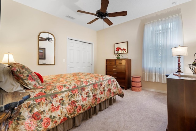 bedroom with a closet, light colored carpet, and ceiling fan