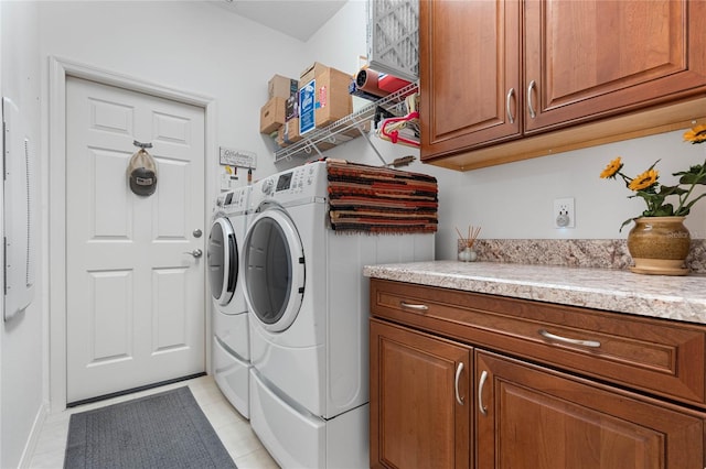 clothes washing area featuring cabinets, washer and dryer, and light tile patterned floors