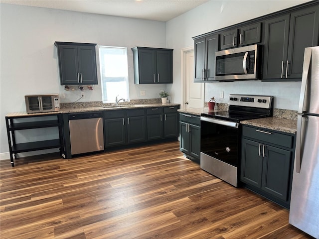 kitchen featuring light stone countertops, sink, stainless steel appliances, and dark hardwood / wood-style floors