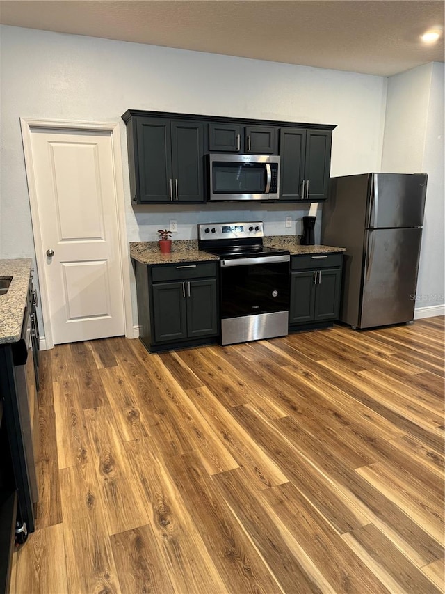 kitchen with stone countertops, dark wood-type flooring, and appliances with stainless steel finishes