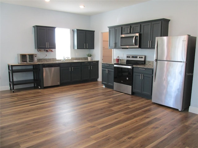 kitchen featuring stone counters, appliances with stainless steel finishes, and dark wood-type flooring