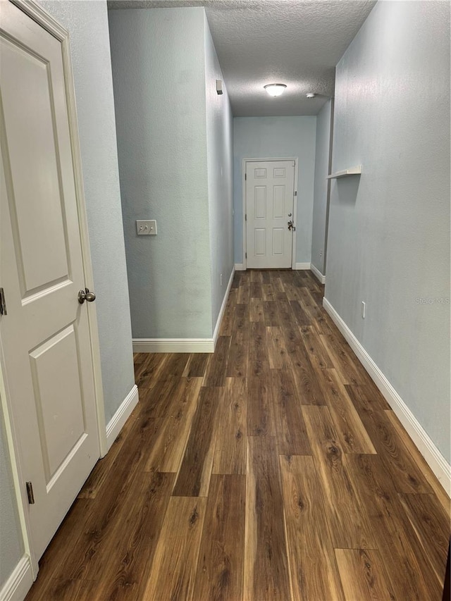 hallway featuring dark hardwood / wood-style flooring and a textured ceiling