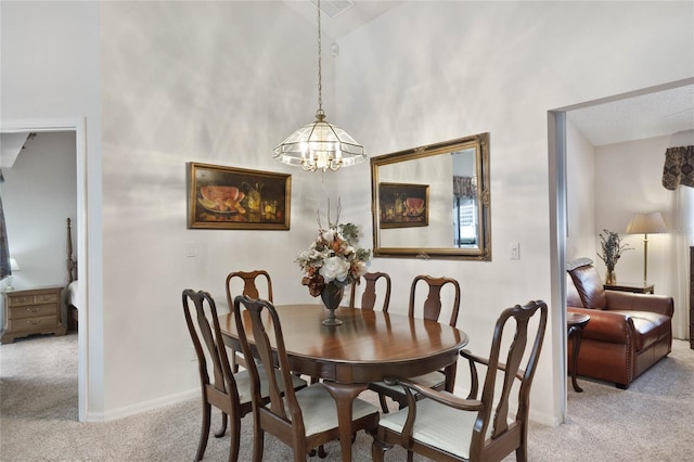 dining area with high vaulted ceiling, light colored carpet, and an inviting chandelier