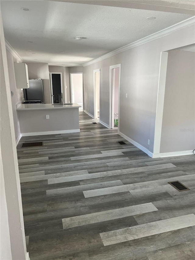 unfurnished living room with crown molding, a textured ceiling, and dark hardwood / wood-style flooring