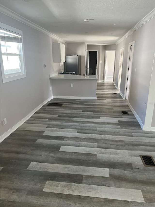 unfurnished living room featuring a textured ceiling, dark hardwood / wood-style floors, and crown molding