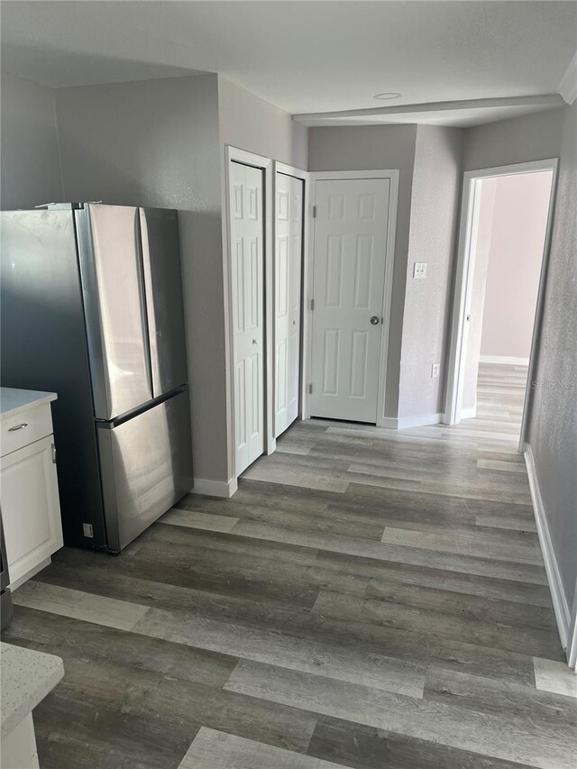 interior space with white cabinetry, dark wood-type flooring, and stainless steel refrigerator