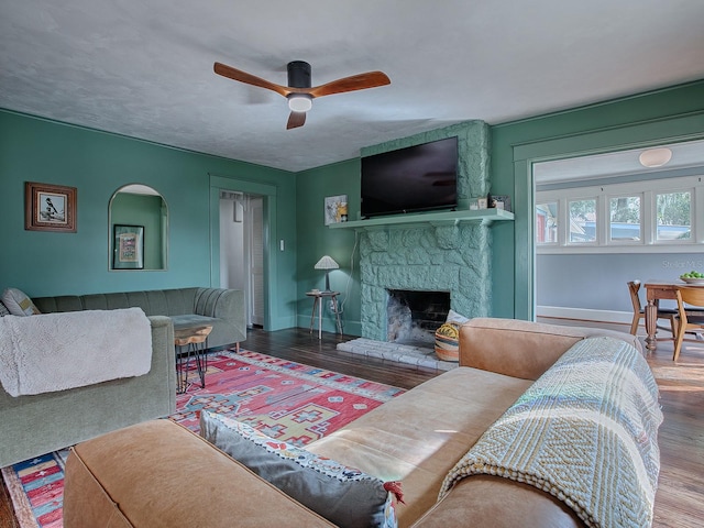 living room featuring a stone fireplace, hardwood / wood-style floors, and ceiling fan