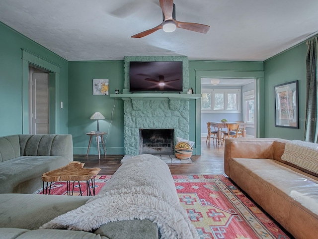 living room featuring hardwood / wood-style flooring, ceiling fan, and a fireplace