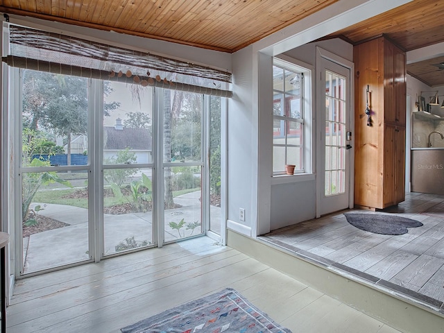 doorway with wood-type flooring, crown molding, and wood ceiling