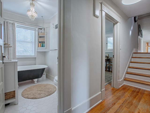 bathroom featuring wood-type flooring, toilet, a chandelier, a bathing tub, and crown molding