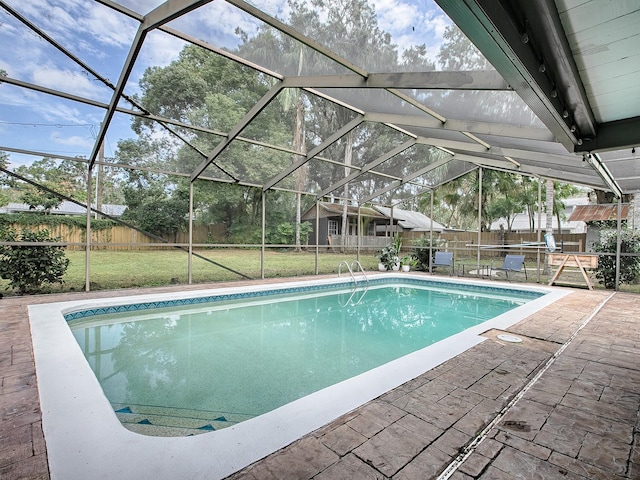 view of pool with a patio, a lawn, and a lanai