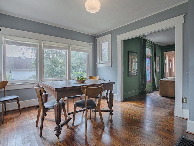 dining area featuring dark hardwood / wood-style flooring, ornamental molding, and a healthy amount of sunlight