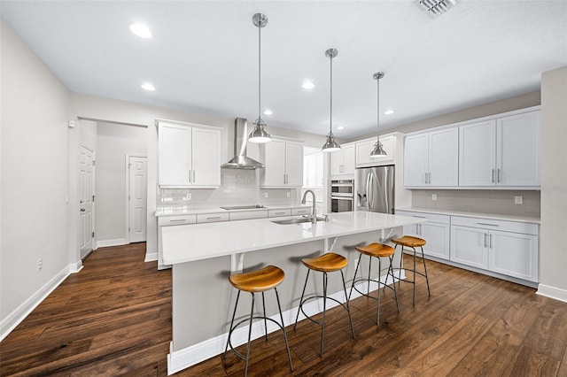 kitchen featuring dark hardwood / wood-style flooring, stainless steel appliances, hanging light fixtures, and wall chimney exhaust hood