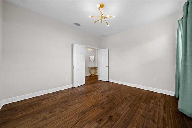 unfurnished bedroom featuring dark hardwood / wood-style flooring and a notable chandelier