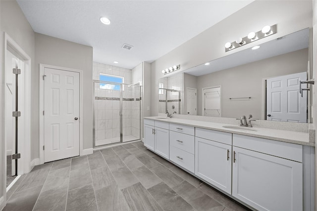 bathroom featuring vanity, an enclosed shower, and a textured ceiling