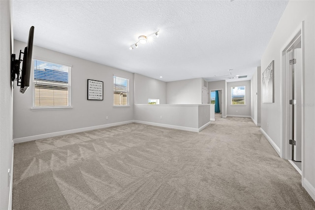 unfurnished room with light carpet, plenty of natural light, and a textured ceiling