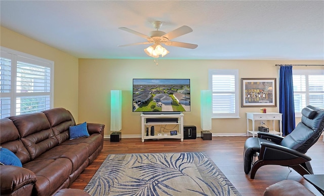 living room featuring dark wood-type flooring and ceiling fan