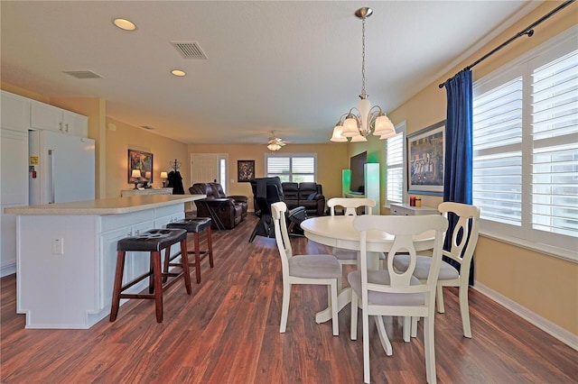 dining area featuring dark wood-type flooring and ceiling fan with notable chandelier