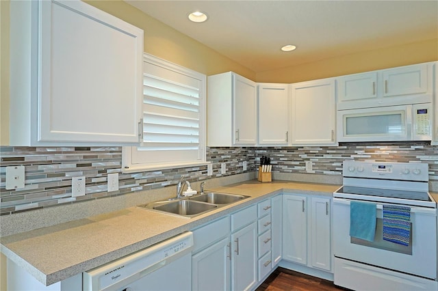 kitchen featuring dark wood-type flooring, white cabinets, sink, backsplash, and white appliances