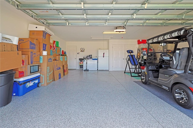 garage featuring white fridge and a garage door opener