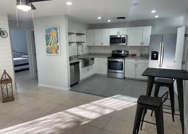 kitchen with white cabinetry, appliances with stainless steel finishes, backsplash, light tile patterned floors, and sink