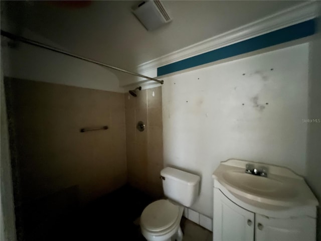 bathroom with toilet, a tile shower, and vanity