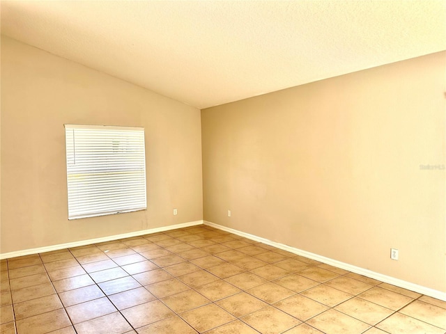 spare room featuring a textured ceiling, light tile patterned floors, and vaulted ceiling