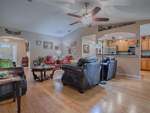 living room featuring arched walkways, ceiling fan, lofted ceiling, and light wood finished floors