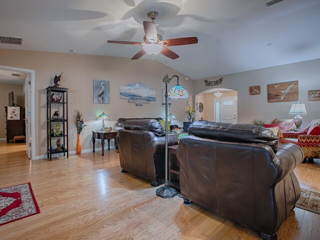 living room featuring a ceiling fan, light wood finished floors, vaulted ceiling, arched walkways, and baseboards