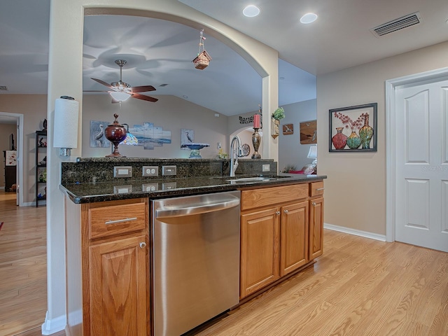 kitchen with light hardwood / wood-style floors, sink, dark stone counters, dishwasher, and vaulted ceiling