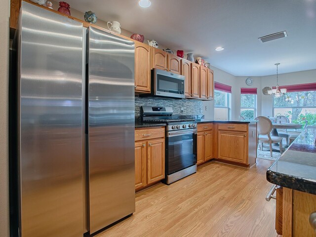 kitchen with stainless steel appliances, dark countertops, light wood-type flooring, tasteful backsplash, and pendant lighting
