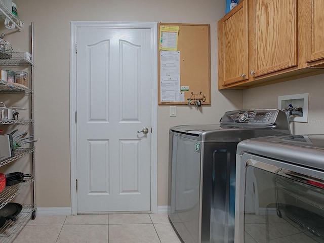 clothes washing area featuring cabinets, washer and dryer, and light tile patterned flooring