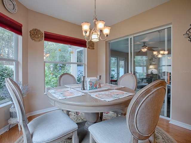 dining area featuring wood-type flooring, ceiling fan with notable chandelier, and plenty of natural light