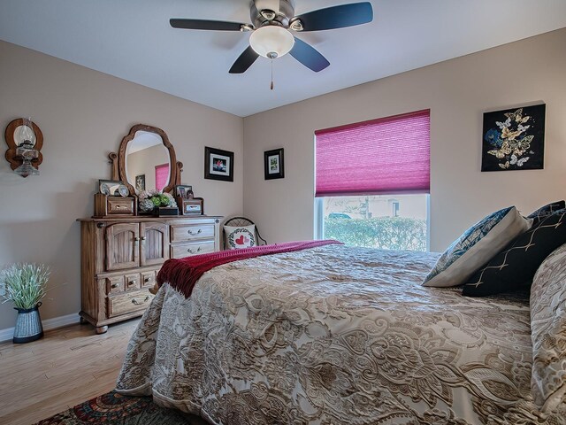 bedroom featuring light wood-style flooring, a ceiling fan, and baseboards