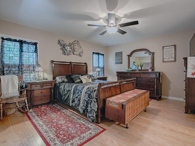 bedroom with light wood-style floors, a ceiling fan, and baseboards