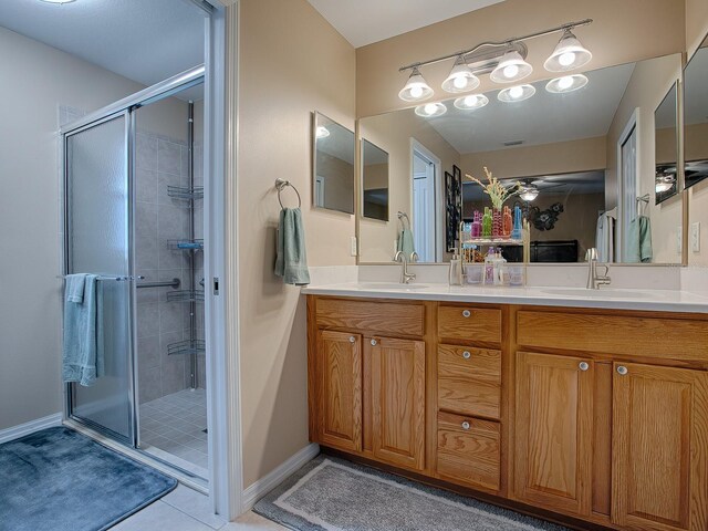 full bath with a stall shower, double vanity, baseboards, and tile patterned floors