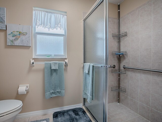 full bath with a stall shower, toilet, and baseboards