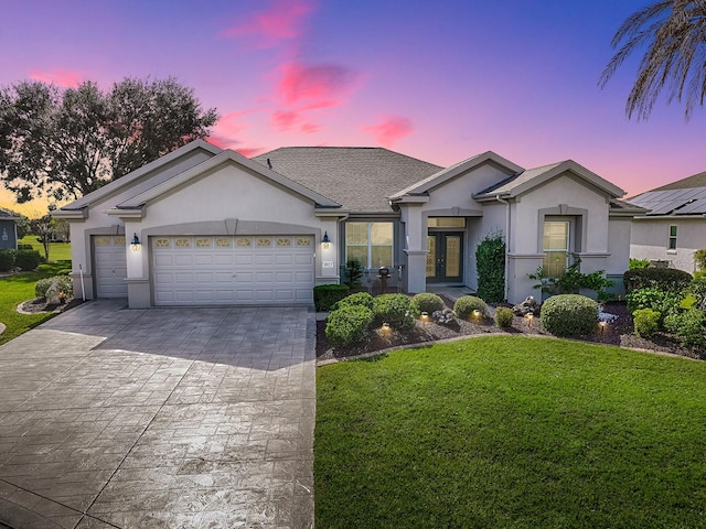 ranch-style home featuring a garage, a yard, and french doors