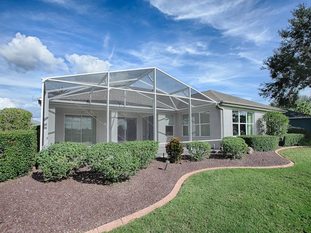 back of property with glass enclosure and a lawn