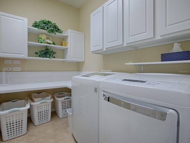 clothes washing area with light tile patterned flooring, cabinets, and washer and dryer