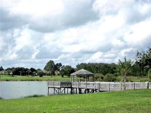 dock area with a water view, a lawn, and a gazebo